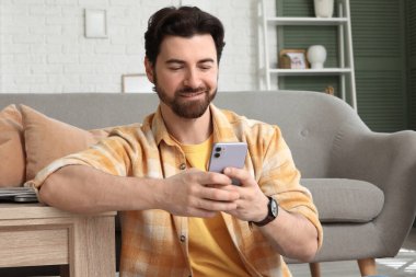 Evde cep telefonu kullanan yakışıklı bir adam.