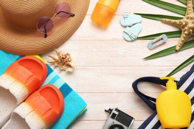 Güneş kremi şişelerinden yapılmış çerçeve ve beyaz ahşap arka planda plaj aksesuarları.
