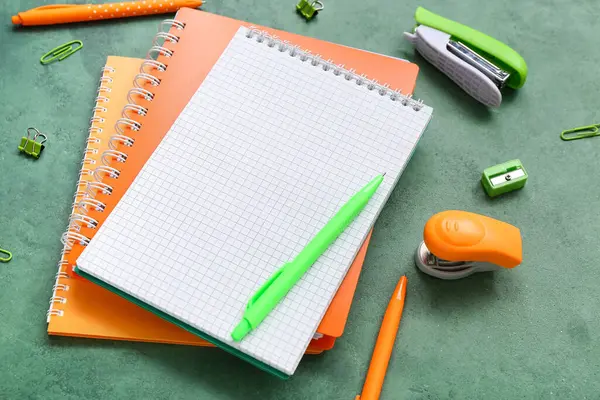 Boş defter ve grunge yeşil arkaplan üzerindeki farklı kırtasiye