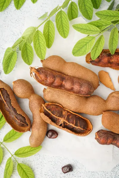 Beyaz arka planda lezzetli tamarindler, yapraklar ve tohumlar