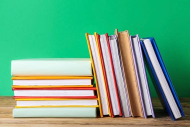 Birçok renkli kitap yeşil arka plana karşı ahşap masa üzerinde