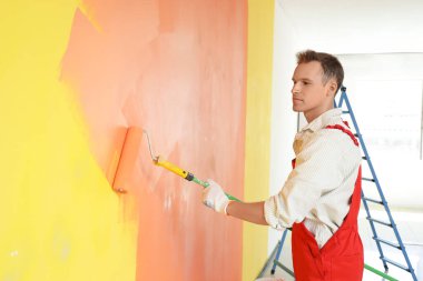 Odasında paten boyama duvarı olan erkek dekoratör.