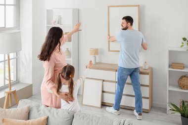 Mutlu bir aile evdeki ışık duvarına boş bir çerçeve asıyor.