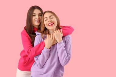 Pembe arka planda sarılan kız arkadaşlar