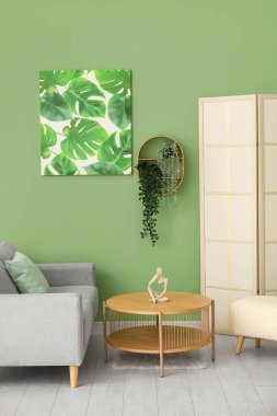 Gri kanepe, puf ve boyalı oturma odasının içinde.