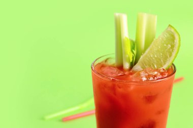 Yeşil zemin üzerinde kereviz ve limon olan bir bardak Bloody Mary.