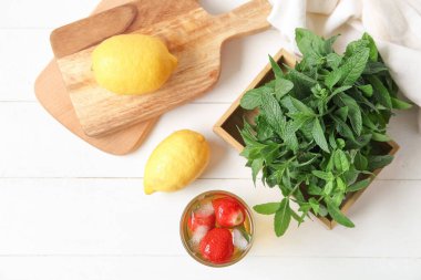 Beyaz arka planda çilekli ve naneli bir bardak buzlu çay.