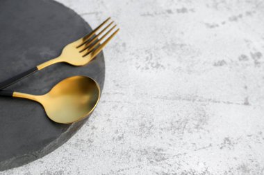 Gri zemin üzerinde çatal ve altın kaşık olan tahta