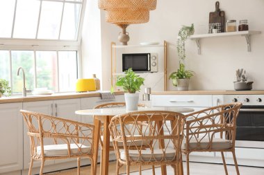 Beyaz tezgahlı, yemek masalı ve büyük pencereli aydınlık mutfağın içi.