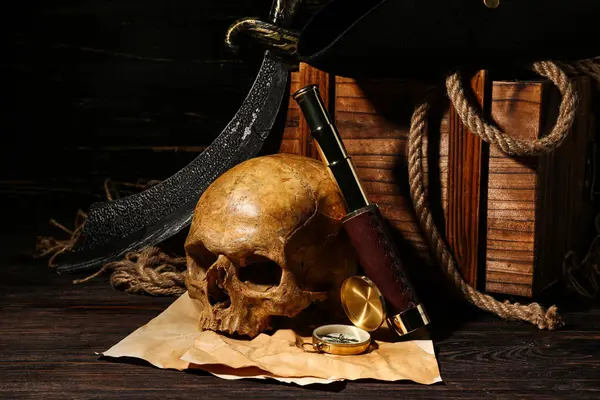 İnsan kafatası, kılıç, dürbün ve pusula kahverengi ahşap arka planda.