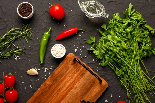 Ahşap mutfak tahtası, taze sebzeler, koyu arkaplanda otlar ve baharatlar.