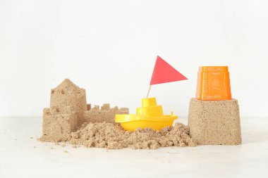 Plaj oyuncaklarıyla kumdan kale ve beyaz arka planda bayrak