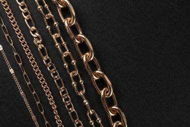 Güzel zincir bilezikler ve siyah arka planda kolyeler.