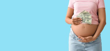 Genç hamile bir kadın mavi arka planda para tutuyor, mesaj için yeri var, yakın plan. Annelik yardımı kavramı