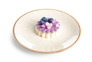 Beyaz arka planda yaban mersinli panna cotta tabağı ve güzel çigila çiçekleri.