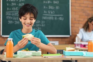 Küçük çocuk öğle yemeğini sınıfta yiyor.