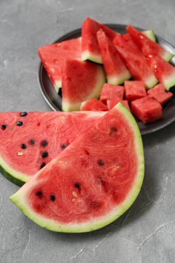 Gri zemin üzerinde taze karpuz parçaları olan bir tabak.