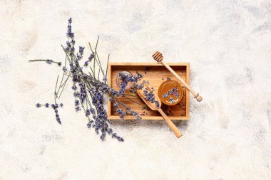 Beyaz arka planda bir kavanoz tatlı lavanta balı, derisi ve çiçekli ahşap kutu.