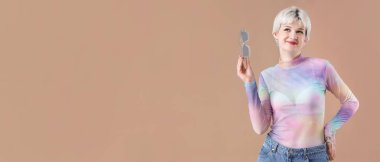 Portrait of beautiful young woman with sunglasses on brown background