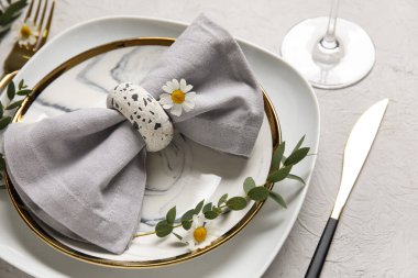 Katlanmış peçeteli tabaklar, altın çatal bıçak takımı ve grunge beyaz arka planda cam.