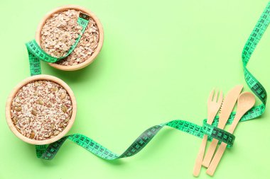 Farklı tohumlar, çatal bıçak takımı ve yeşil arka planda mezura. Diyet kavramı