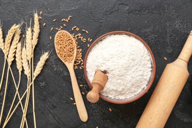 Buğday unu, oklavalı iğne ve siyah grunge arkaplanlı dikenli kase