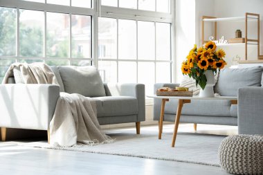 Oturma odasının içinde vazoda ayçiçekleri ve masada kahvaltı.