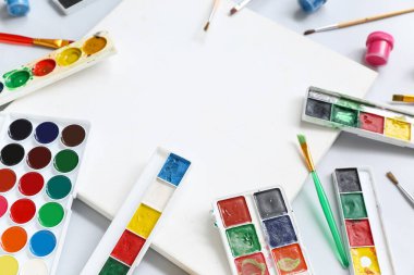 Boş tuval, gri arkaplanda boya ve fırçalar