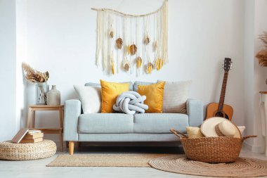 Kanepe, hasır sepet ve gitarla aydınlık oturma odasının içinde.