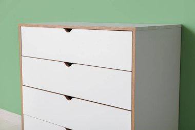 Yeşil duvarın yanındaki beyaz çekmeceler, yakın plan.