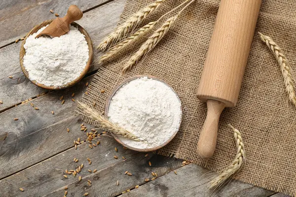 Tahta masa üzerinde buğday unu ve oklavalı kase.