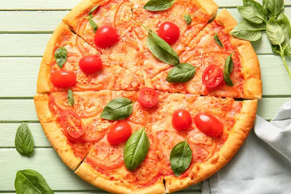 Yeşil ahşap arka planda lezzetli pizza margaritası.