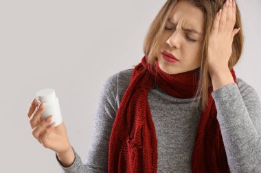 Arka planda ilaç şişesi olan genç bir kadın, yakın plan.