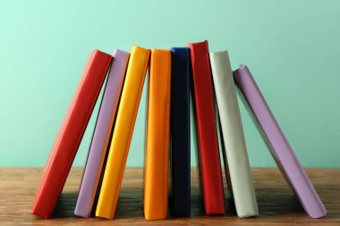 Birçok renkli kitap ahşap masa üzerinde turkuaz arka plana karşı