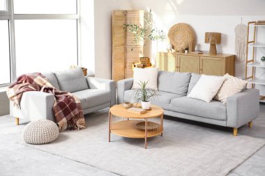 Gri koltukları, kahve masası ve büyük pencereli şık bir oturma odası.