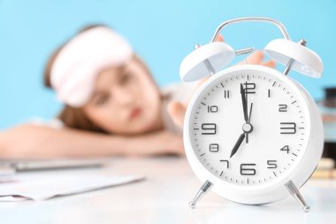 Alarm saati ve mavi arka planda uykulu kadın.