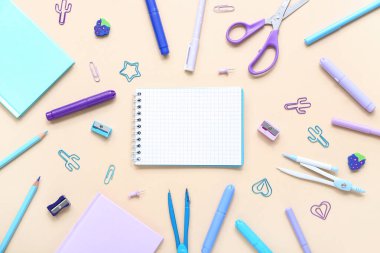 Turuncu arka planda farklı kırtasiye malzemesi içeren defterler