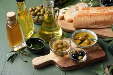 Yeşil ahşap arka planda taze zeytinyağı kaseleri ve bardaklar.