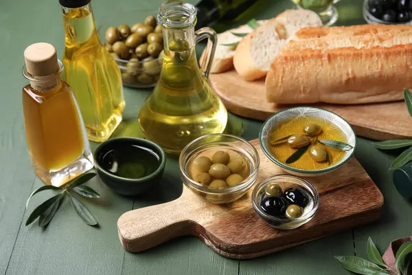 Yeşil ahşap arka planda taze zeytinyağı kaseleri ve bardaklar.