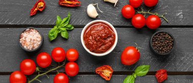 Lezzetli domates sosu ve siyah ahşap masa üzerindeki malzemelerle kompozisyon.