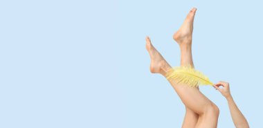 Yumuşak tüylü, açık mavi arkaplanlı, metin için yeri olan güzel genç bayanların bacakları. Epilasyon kavramı