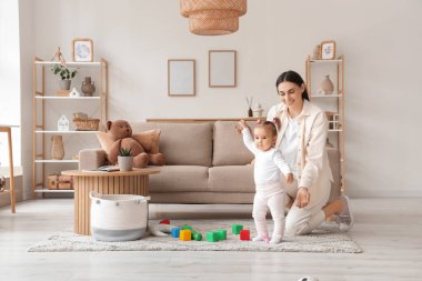 Anne evde bebeğiyle oynuyor.