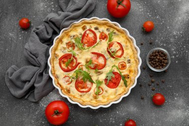 Lezzetli roka yapraklı domates turtası ve koyu arkaplanda bir kase biber.