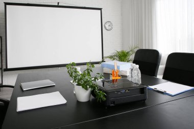 Modern ofiste masa, ev bitkileri ve projektör ekranlı konferans salonu.