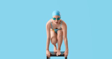 Açık mavi arkaplanda başlangıç pozisyonunda kadın yüzücü 