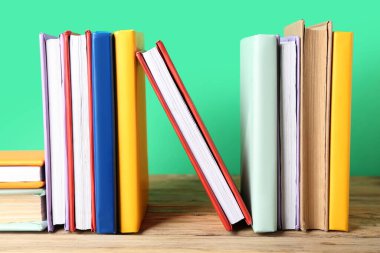 Birçok renkli kitap yeşil arka plana karşı ahşap masa üzerinde