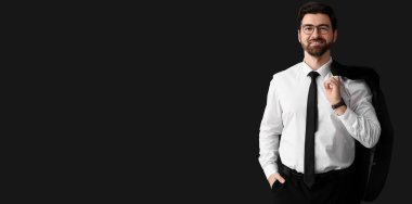 Siyah arka planda şık takım elbiseli yakışıklı bir iş adamı.