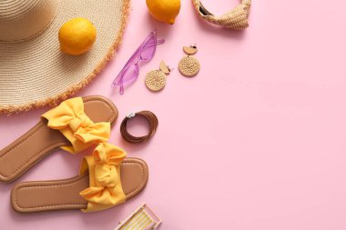 Pembe arka planda plaj aksesuarları ve limonları olan kompozisyon