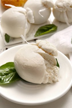 Beyaz arka planda fesleğenli lezzetli Burrata peyniri tabağı.