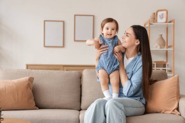 Anne ve bebeği evdeki kanepede oturuyor.